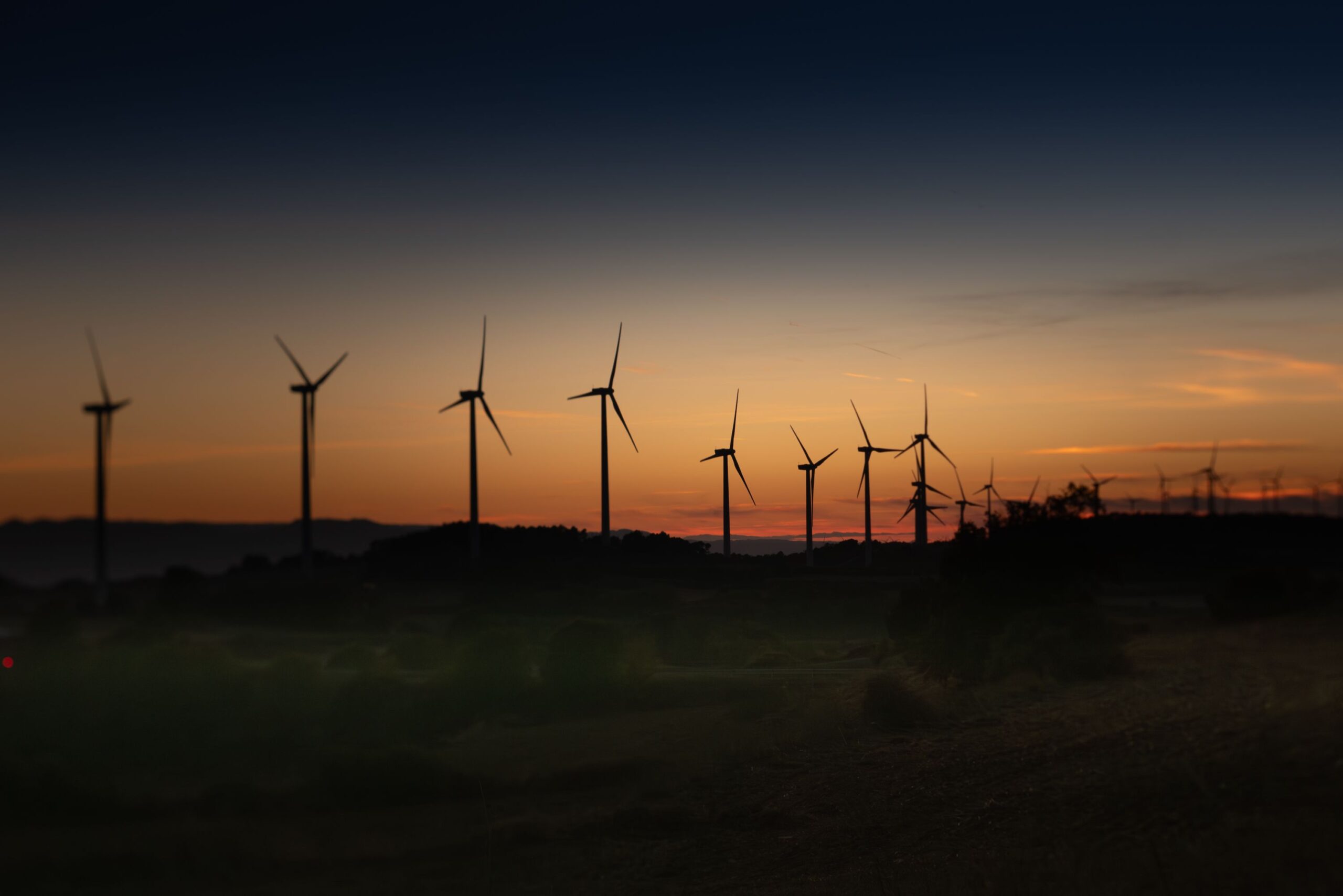 Silhouettes of wind turbines against a vibrant sunset in Lleida, Spain.